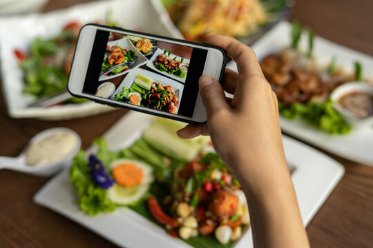 Woman take picture of a meal on the table after ordering food online to eat at home. Photography and use phone concepts