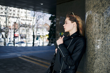 woman in leather jacket on the street in the city and edition sunglasses in the background