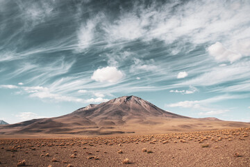 Fototapeta na wymiar Mountain with light brown grass under cloudy blue sky