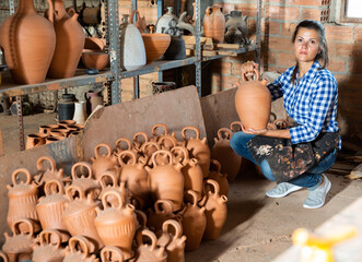 Fototapeta na wymiar Female artisan in apron having ceramics in stock. High quality photo