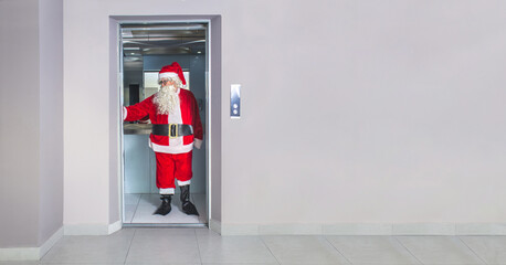Man disguised as Santa Claus, inside an elevator in a building at Christmas