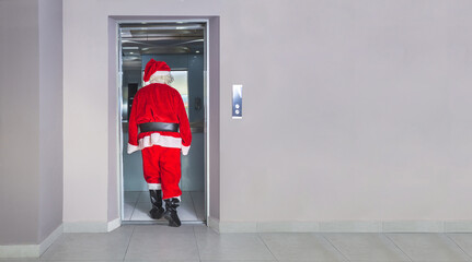 Man disguised as Santa Claus, Santa Claus entering the elevator in a building at Christmas © FABIAN PONCE GARCIA