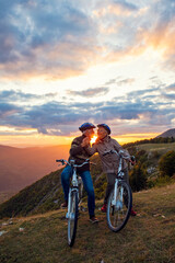 Fototapeta na wymiar elderly couple with bicycles standing at the mountain park kissing