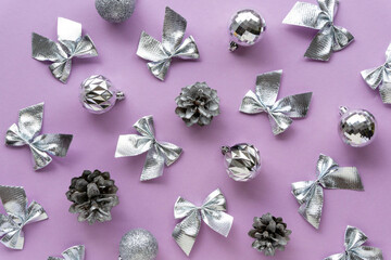 Christmas or new year flat lay of decorations. Silver bows, balls and cones on a lilac background