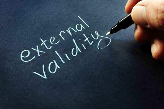 Hand is writing External validity on the black paper.