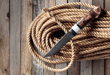 Fototapeta premium Hunter combat hand made knife and hemp rope on wooden background.
