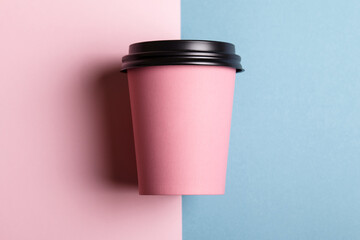 Pink paper cup of coffee to go or tea on pink and blue pastel background. Mock-up for branding. 