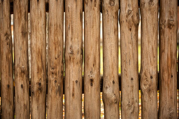 A fence made of roughly processed boards. A palisade of rough logs. Wood back