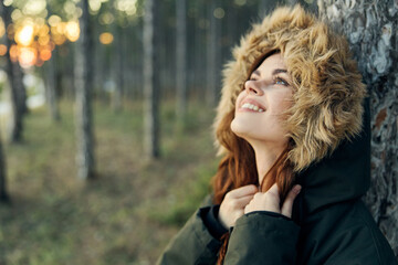 Smiling woman in a hooded jacket looks upstairs in the fresh air