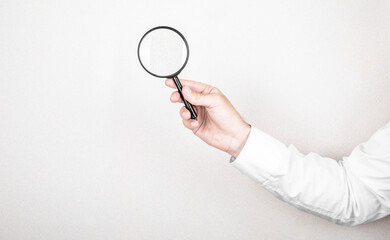 Fototapeta na wymiar Man holds magnifying glass on wall background. Concept of search, recruitment and job search.
