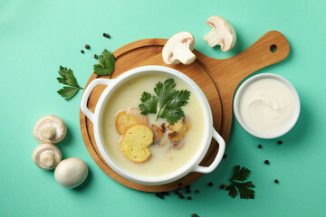 Concept of tasty lunch with bowl of mushroom soup on mint background
