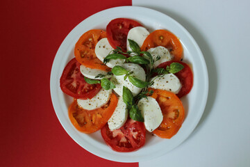 On a white and red background a plate with tomatoes and cheese