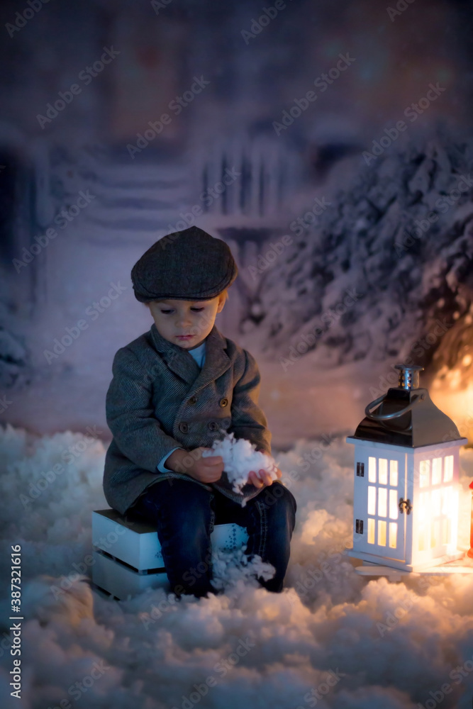 Canvas Prints Little boy, looking at flame from match, sitting in the snow