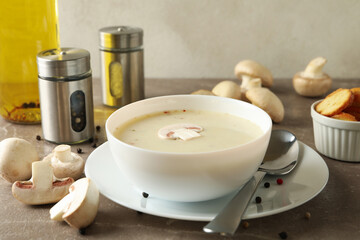 Concept of tasty lunch with bowl of mushroom soup on gray background