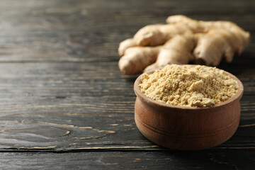 Ginger and bowl with ginger powder on wooden background