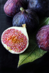 A slice of ripe figs with a green leaf on a dark background close-up
