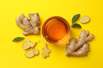 Fresh ginger and cup of tea on yellow background