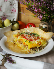 Casserole with minced meat under a cheese crust and a slice of tomato with herbs