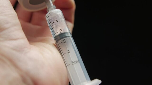 Vaccine into a syringe 5 milliliters closeup black background isolated