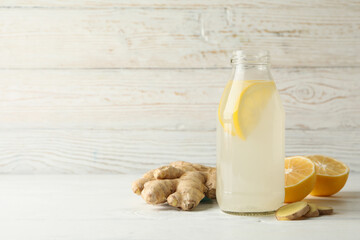 Bottle of ginger lemon water on white wooden background