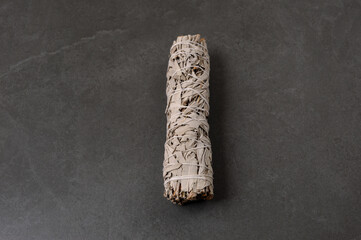 Dried white sage smudge stick on the gray background.
