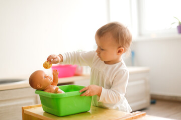 Toddler toddler bathes a toddler doll in a basin of water and a sponge, montessori and earlier child development