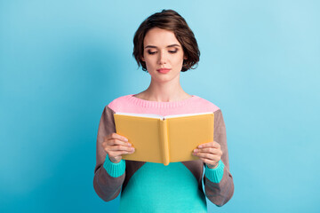 Photo portrait of clever girl holding yellow book in two hands isolated on pastel light blue...