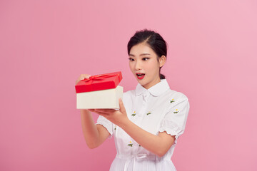 Surprised happy content curly young female looking inside present box on pink background