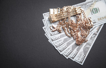 Hundred dollars with a gold jewelry on black background.