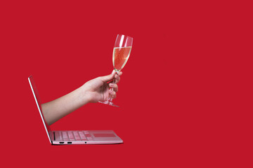 Giving a glass of champagne from the screen of the computer online red background celebration...