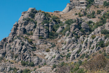 Ridge of brown rocks covered with greenery against a blue sky