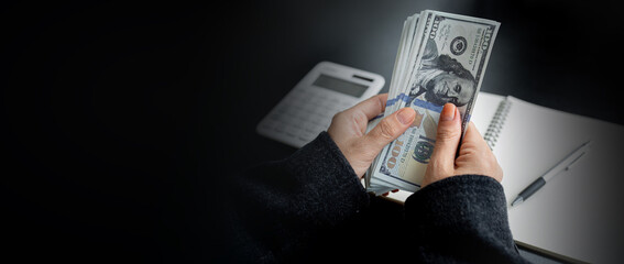 A Businesswoman with American US dollars ,Bundle of one hundred dollar banknotes in female hand on...