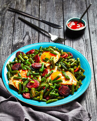 Green beans fried eggs and chorizo on a blue plate