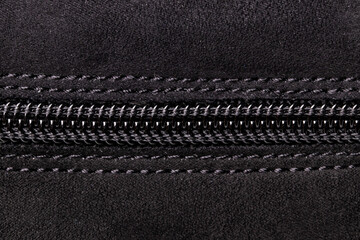 Zip fastener background texture. A high-resolution closeup of a detail from a closed plastic zip fastening on black suede shoe. Macro photo.