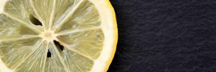 Panoramic image of sliced yellow lemon on black background