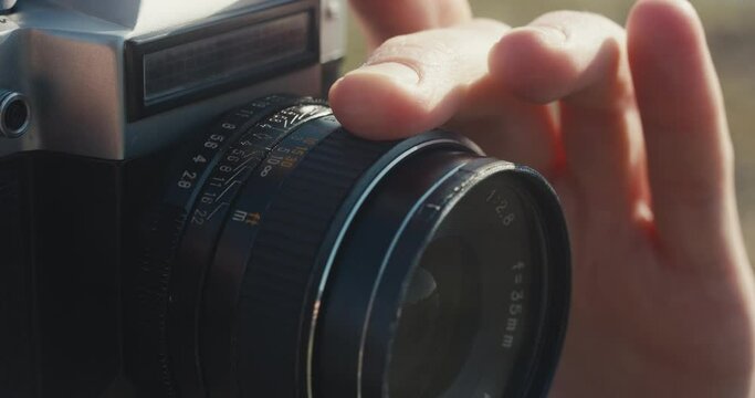 Photographer adjust manual focus lens with finger on analog camera
