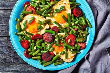 Green beans fried eggs and chorizo on a blue plate