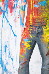 Obraz na płótnie Canvas Young male with jeans full of color paint, studio photo. 