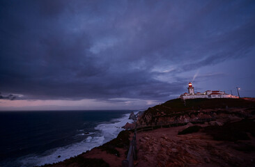 Beam of light shining from lighthouse into a night sky at Cabo da roca in Portugal.