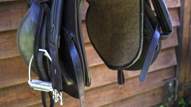 Horse equipment hangs at the entrance to the stables. Black saddle and leather aspiring. High quality 4k footage. 
