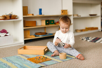 child toddler plays with balls and cylinders, developing sensory activities in montessori and...