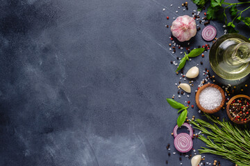 Herbs and condiments on black stone background.