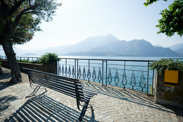 Fototapeta na wymiar Beautifil landscape with bench on the promenade of Como Lake, Italy.