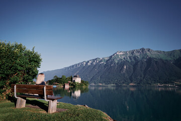 Fototapeta na wymiar Traveling by Switzerland. Young woman siiting on bench enjoying wonderful view on Brienzersee lake.