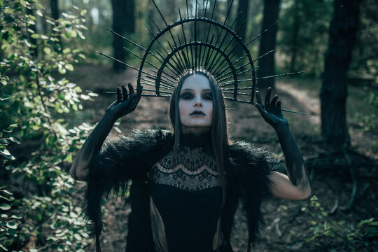 Woman in image of witch stands in forest.