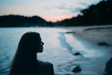 Fototapeta premium Beautiful sunset. Silhouette of young woman on ocean beach.