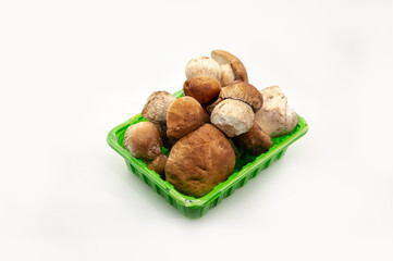 Beautiful fresh porcini mushrooms in green plastic basket on white background healthy food