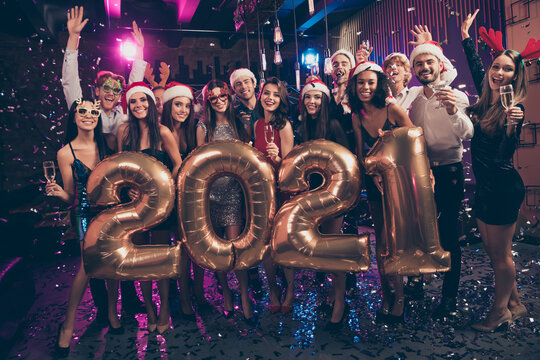 Photo portrait of happy people celebrating new year 2021 raising hands holding champagne glasses wearing goofy festive reindeer headwear