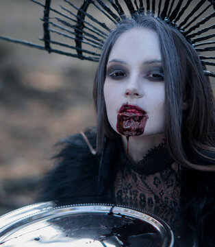 Portrait of woman in image of vampire with bloody face and dish with blood.