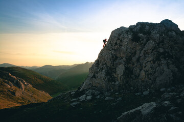 Silueta de un escalador en la vertiente sur de los Picos de Europa con luces del atardecer y unas colinas de fondo